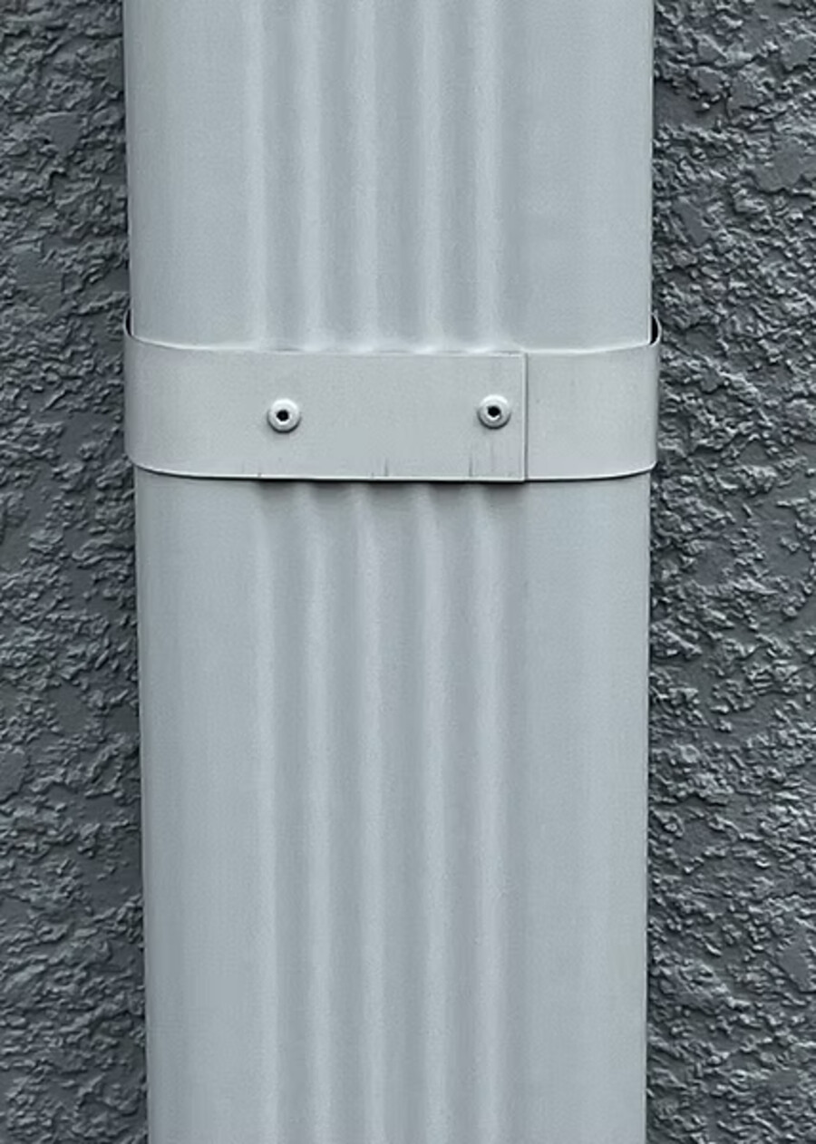 3×4 downspout fixed with a heavy-duty strap against stucco