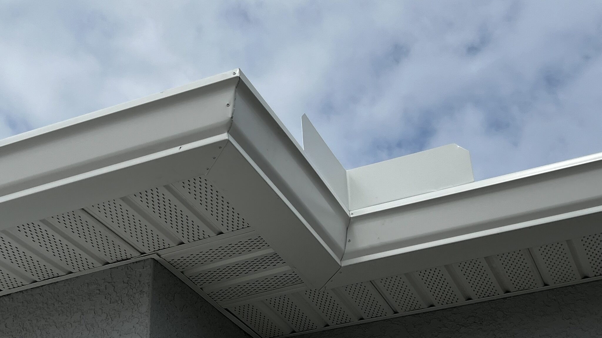 Close-up of a hand-cut mitered corner with rivets on a seamless gutter
